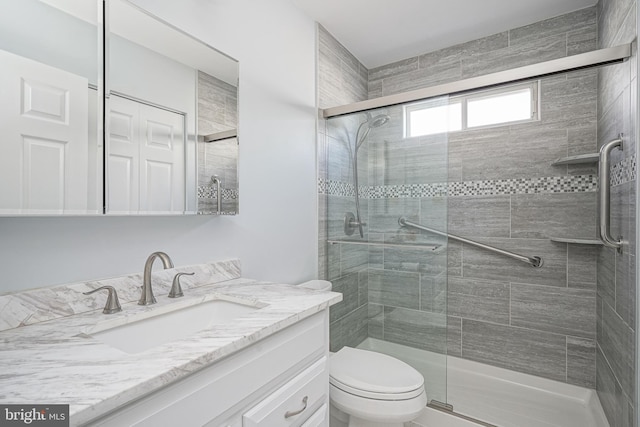 bathroom featuring vanity, a shower with shower door, and toilet