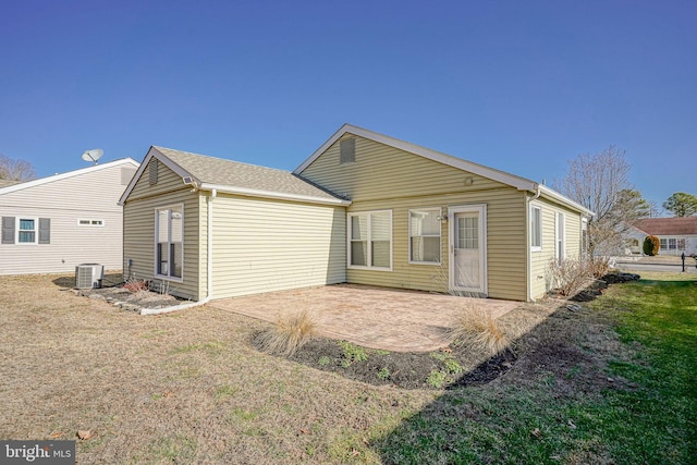 rear view of house with central AC unit, a patio area, and a lawn