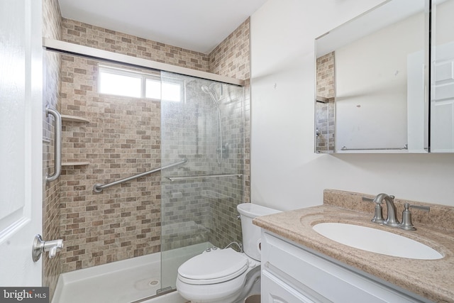 bathroom with vanity, a shower with door, and toilet