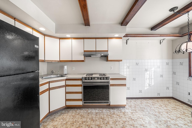 kitchen with black refrigerator, white cabinets, and stove