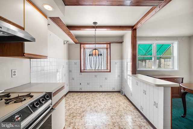 kitchen featuring range with gas cooktop, white cabinetry, pendant lighting, beam ceiling, and exhaust hood