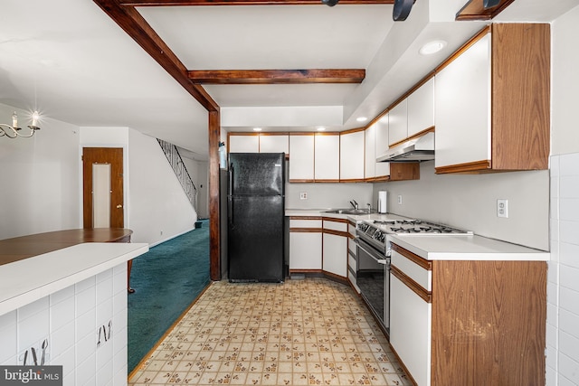 kitchen featuring sink, black fridge, white cabinetry, range, and beam ceiling