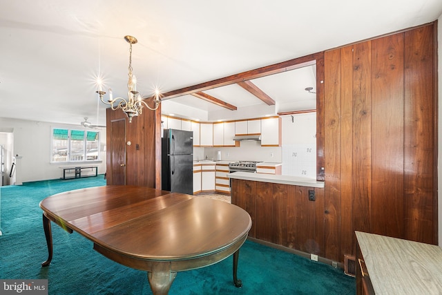 dining area featuring beam ceiling, a notable chandelier, and dark carpet