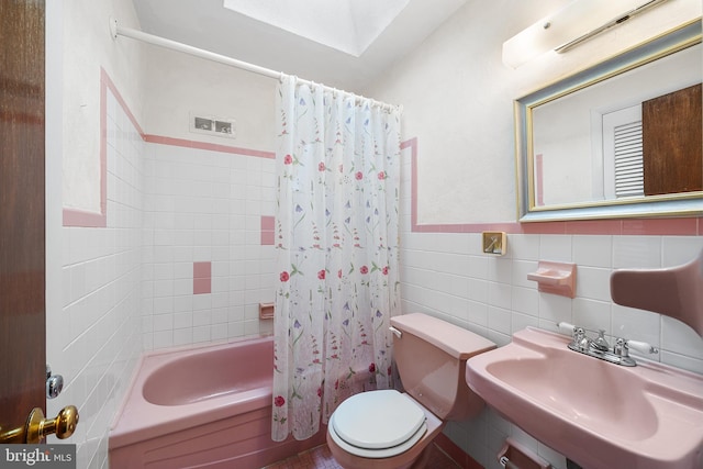 full bathroom with shower / tub combo with curtain, toilet, sink, and tile walls