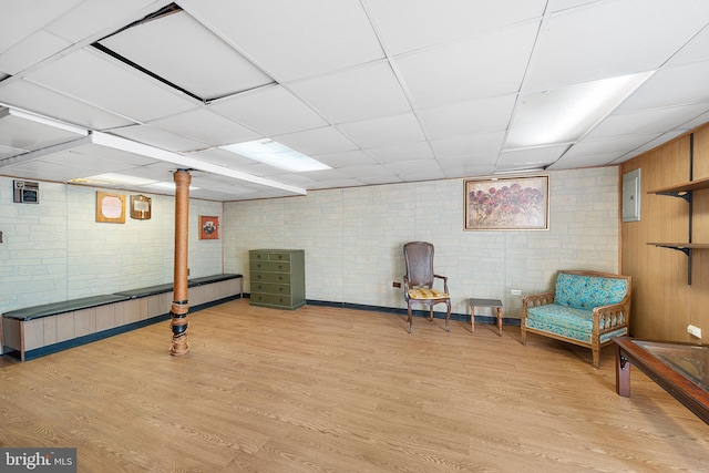 sitting room with a paneled ceiling and light wood-type flooring