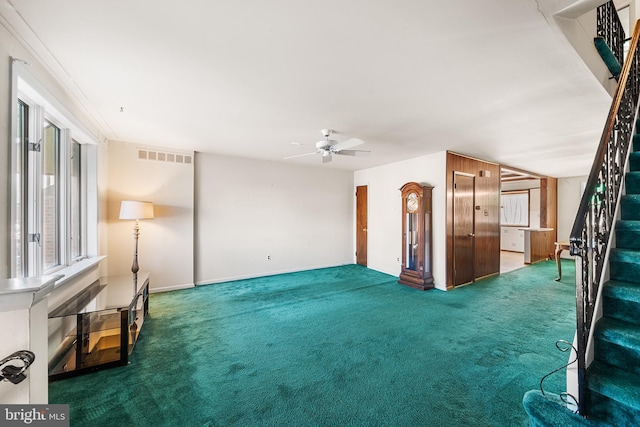 unfurnished living room with dark carpet and ceiling fan