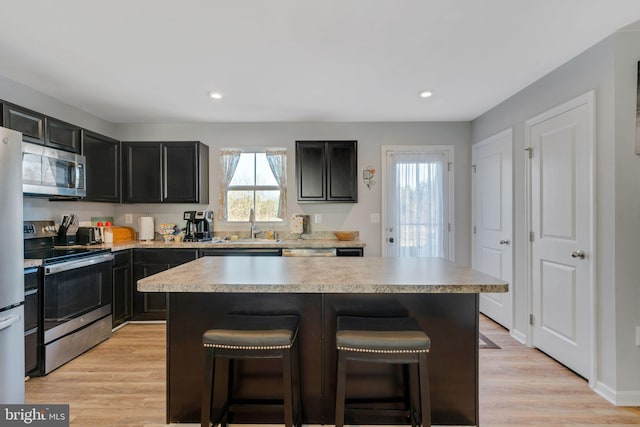 kitchen with stainless steel appliances, a center island, and a kitchen bar