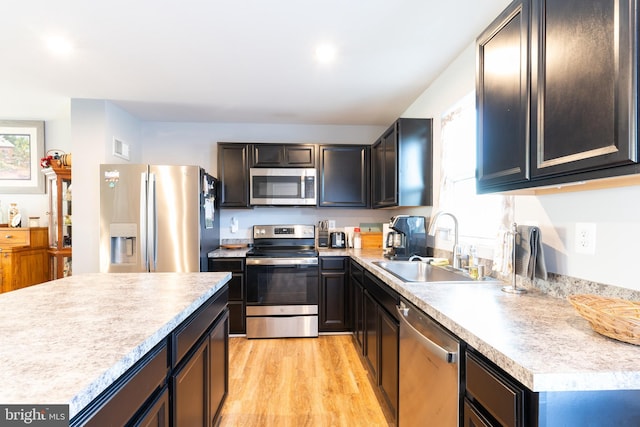 kitchen with stainless steel appliances, sink, and light hardwood / wood-style flooring