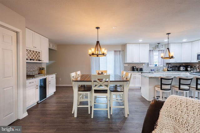 kitchen with pendant lighting, a breakfast bar area, beverage cooler, and white cabinets