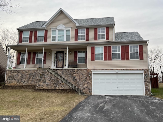 view of front of house featuring a shingled roof, covered porch, an attached garage, stone siding, and driveway