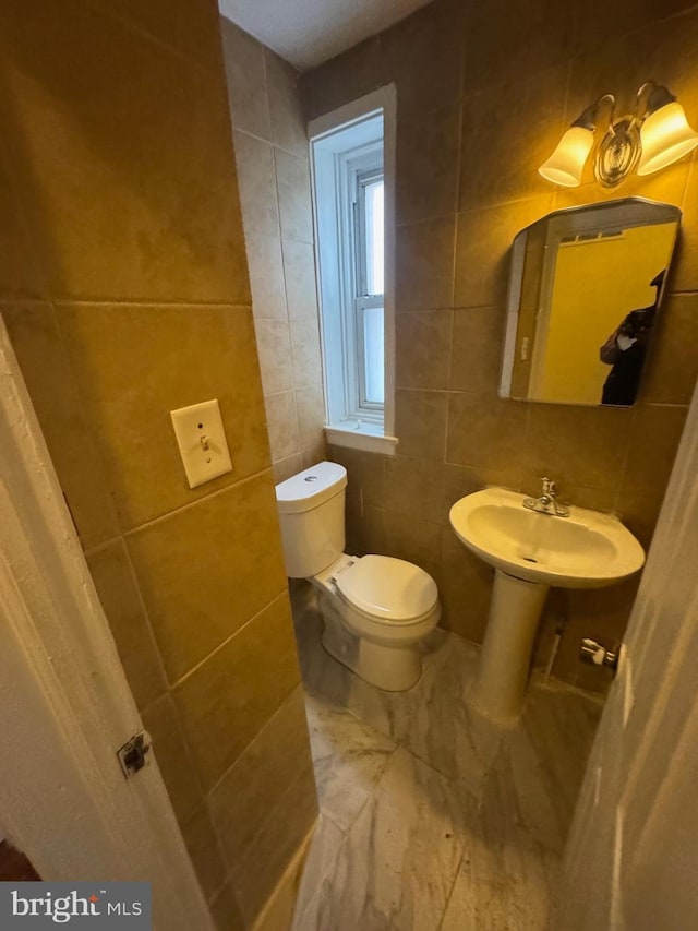 bathroom featuring tile walls, sink, and toilet