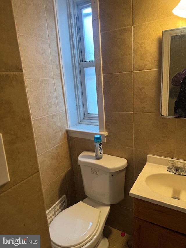 bathroom with vanity, toilet, and tile walls