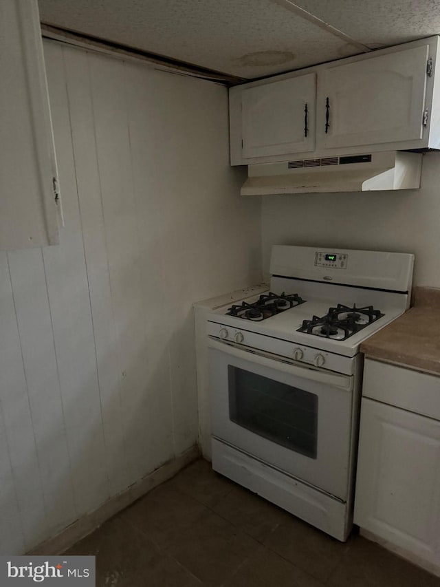 kitchen featuring white cabinetry, dark tile patterned flooring, and white gas range oven