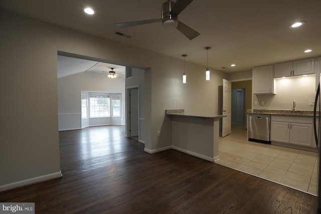 kitchen featuring a peninsula, wood finished floors, visible vents, dishwasher, and dark stone countertops