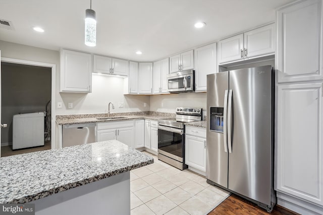 kitchen with recessed lighting, a sink, white cabinetry, appliances with stainless steel finishes, and light stone countertops