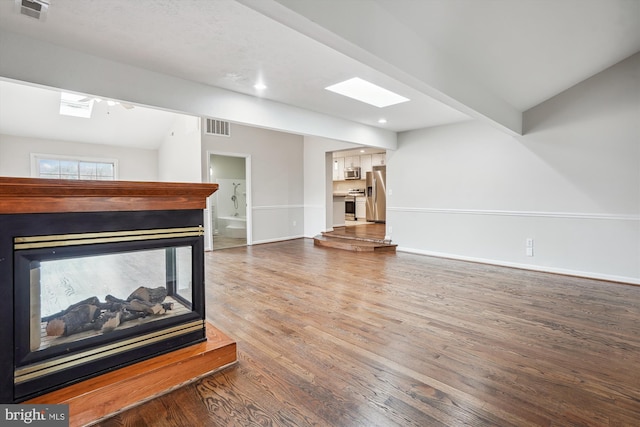 living area with baseboards, visible vents, a multi sided fireplace, and wood finished floors