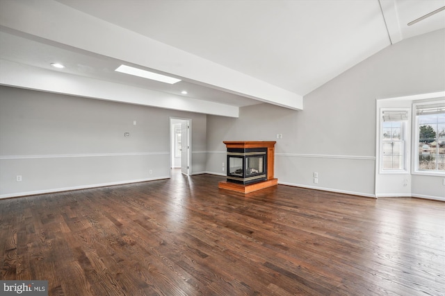 unfurnished living room with vaulted ceiling with skylight, wood finished floors, a multi sided fireplace, and baseboards