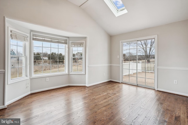 unfurnished room with vaulted ceiling with skylight, baseboards, and wood finished floors