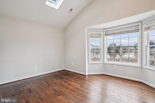 spare room featuring lofted ceiling with skylight, visible vents, baseboards, and wood finished floors