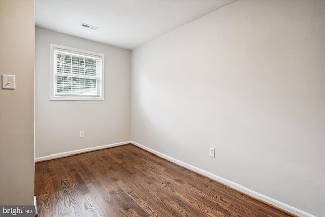 spare room featuring baseboards, visible vents, and dark wood-type flooring