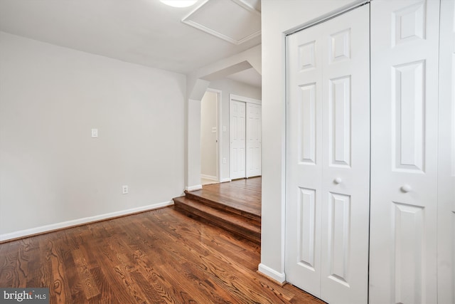 empty room featuring attic access, baseboards, and wood finished floors