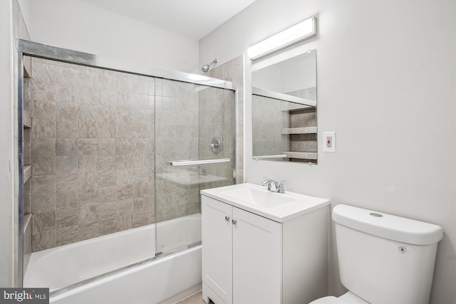 bathroom featuring enclosed tub / shower combo, vanity, and toilet