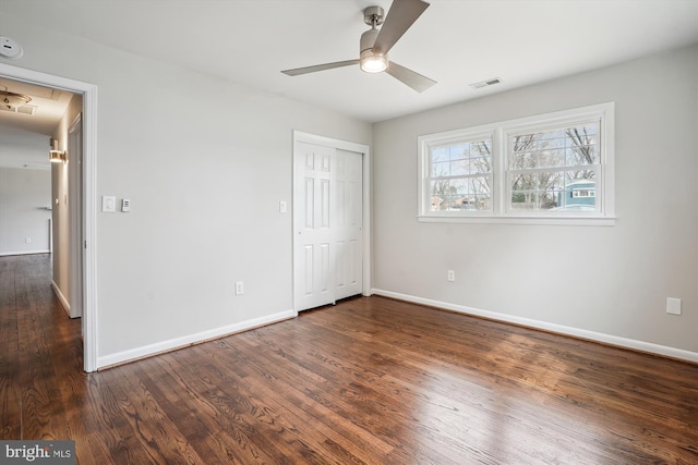 unfurnished bedroom featuring dark wood-style flooring, visible vents, baseboards, a closet, and attic access