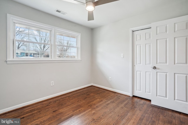 unfurnished bedroom with ceiling fan, visible vents, baseboards, a closet, and dark wood-style floors