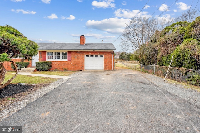 view of front of property featuring an attached garage, brick siding, fence, driveway, and a chimney