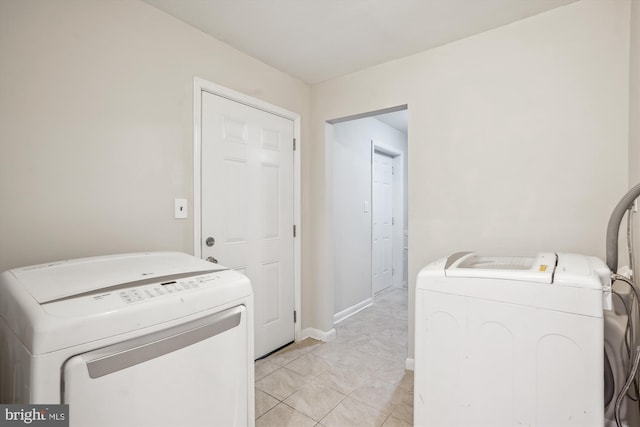 laundry area with laundry area, separate washer and dryer, and baseboards