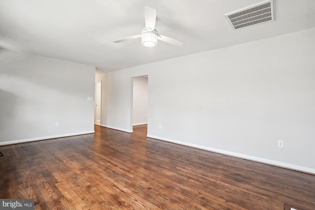 spare room with a ceiling fan, baseboards, visible vents, and dark wood-style flooring