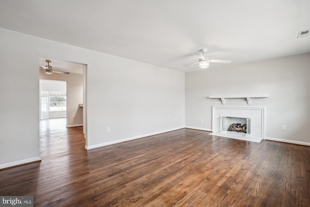 unfurnished living room with visible vents, baseboards, dark wood finished floors, a ceiling fan, and a brick fireplace