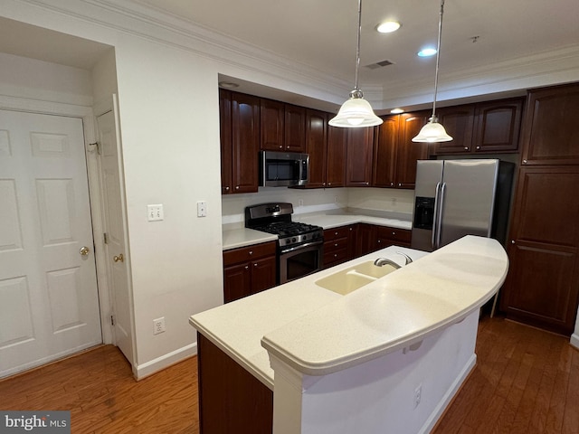 kitchen with pendant lighting, appliances with stainless steel finishes, a kitchen island with sink, and dark brown cabinets