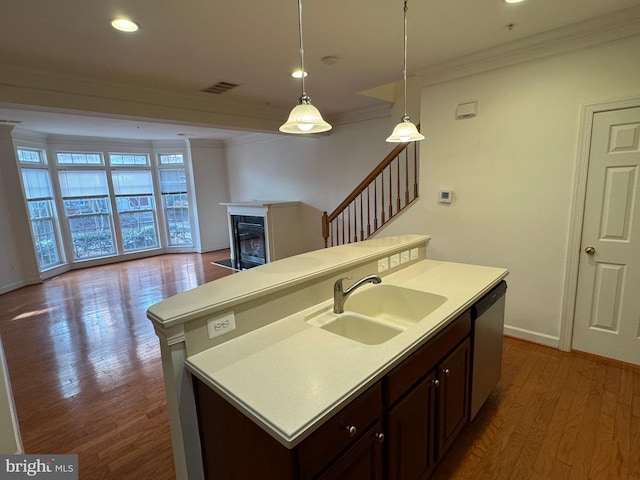 kitchen with sink, hanging light fixtures, dark brown cabinetry, ornamental molding, and stainless steel dishwasher