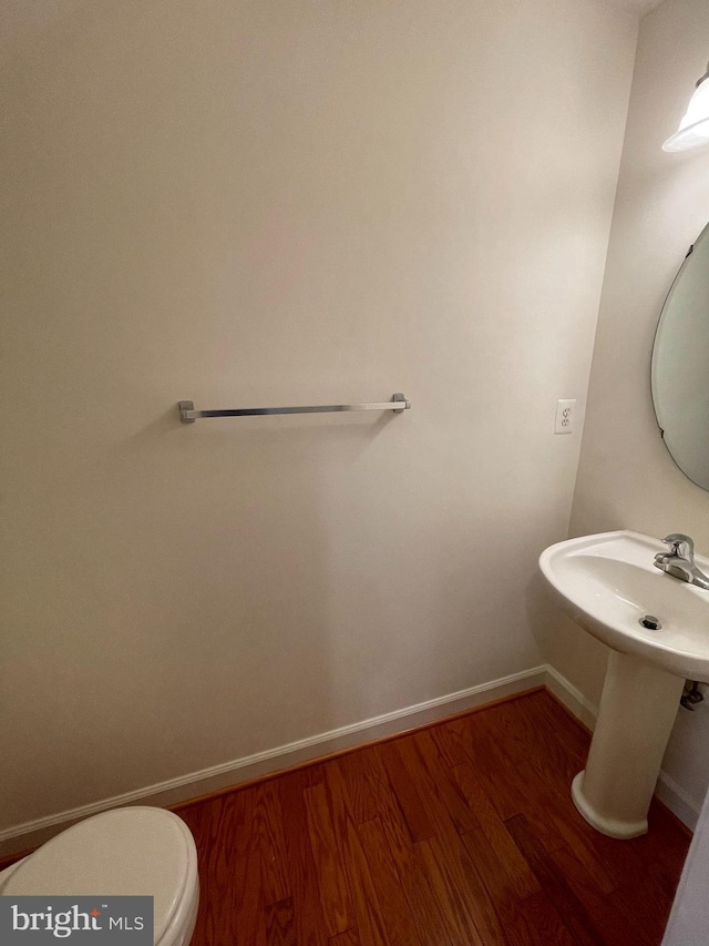 bathroom featuring wood-type flooring, toilet, and sink