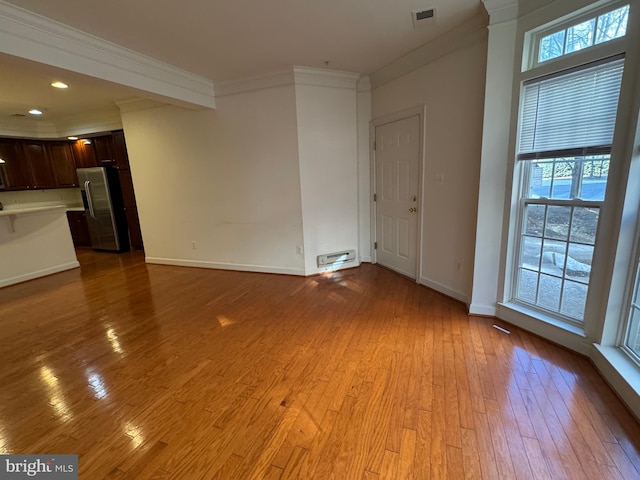 unfurnished living room featuring ornamental molding and light hardwood / wood-style flooring