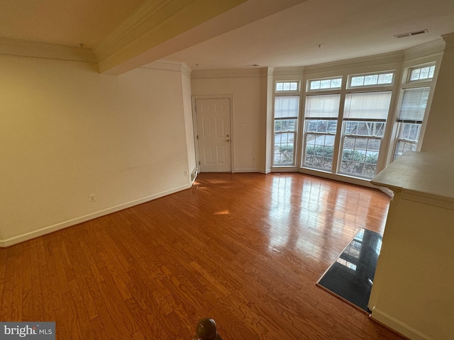 unfurnished living room with ornamental molding and hardwood / wood-style floors