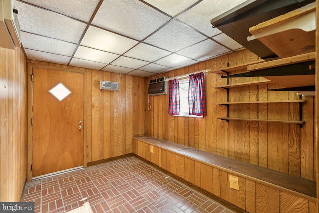 mudroom with wooden walls, a wall unit AC, and a paneled ceiling