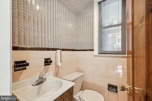 bathroom featuring vanity, toilet, and tile walls