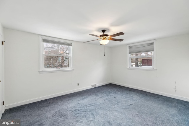 empty room with dark colored carpet and ceiling fan