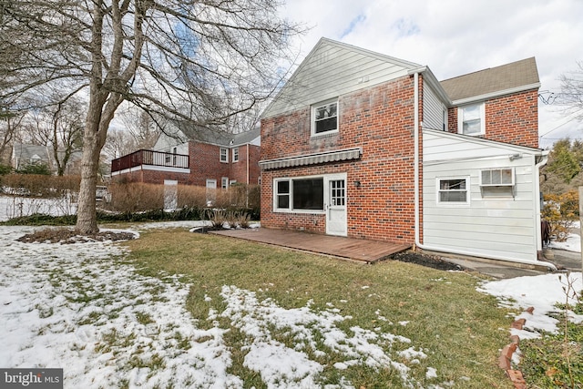 snow covered rear of property with a yard, a wall mounted air conditioner, and a deck