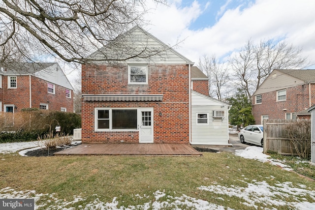 snow covered rear of property with a wooden deck and a yard