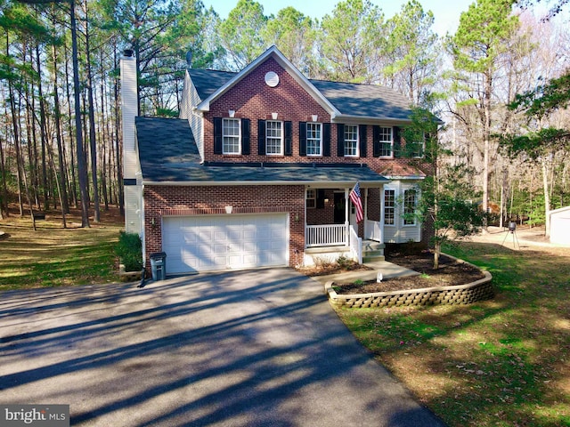 colonial-style house featuring a garage and covered porch