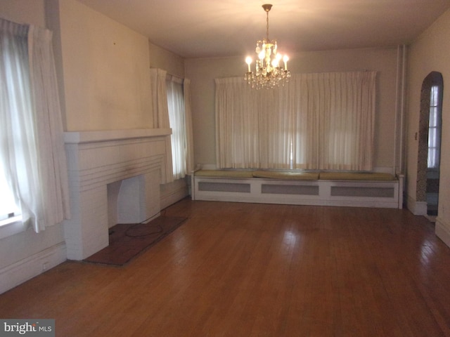 unfurnished dining area featuring a notable chandelier and dark hardwood / wood-style floors