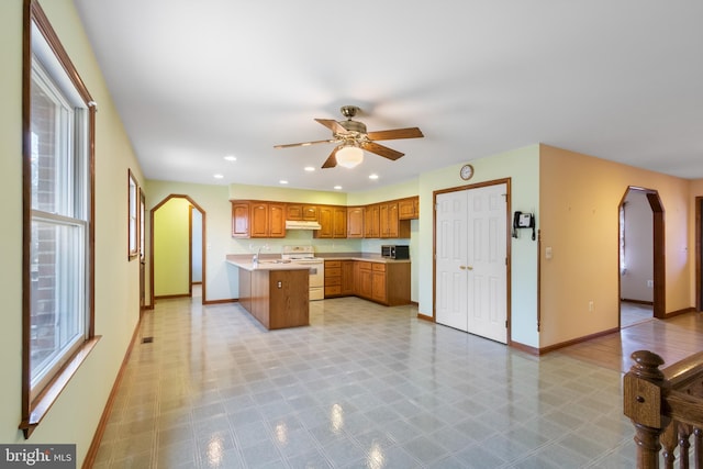 kitchen featuring electric stove, ceiling fan, sink, and a wealth of natural light