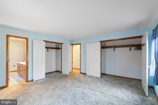 unfurnished bedroom featuring light colored carpet and ensuite bath