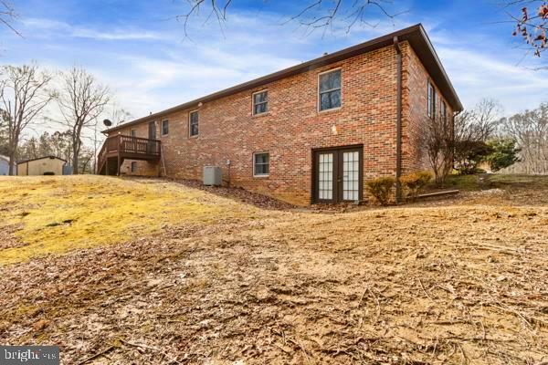 view of side of home with french doors, central AC unit, and a wooden deck