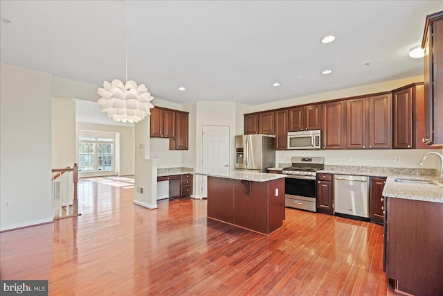 kitchen with sink, a breakfast bar area, hanging light fixtures, a kitchen island, and stainless steel appliances