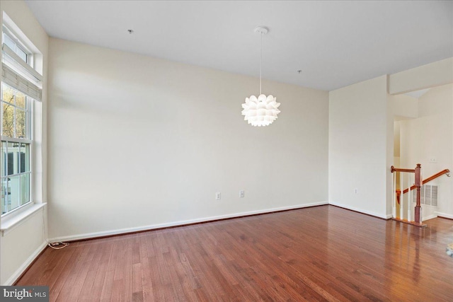 unfurnished room with a notable chandelier and dark hardwood / wood-style flooring