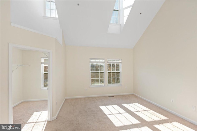 empty room featuring a wealth of natural light, a towering ceiling, and light carpet